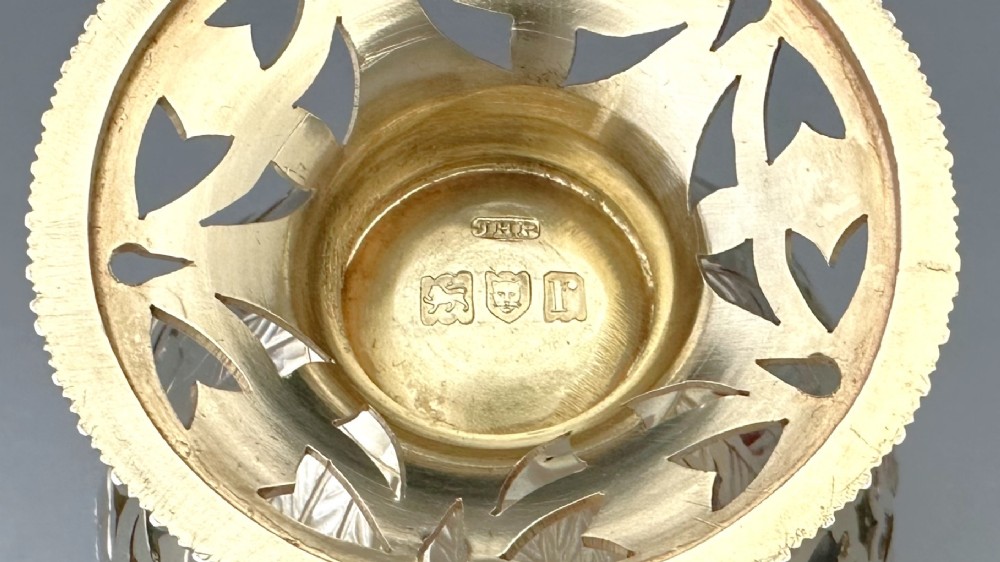 A pierced silver-gilt sugar basket featuring drape and bow motifs with an overhead swing handle, housing a scalloped ruby red cranberry glass liner. View IX
