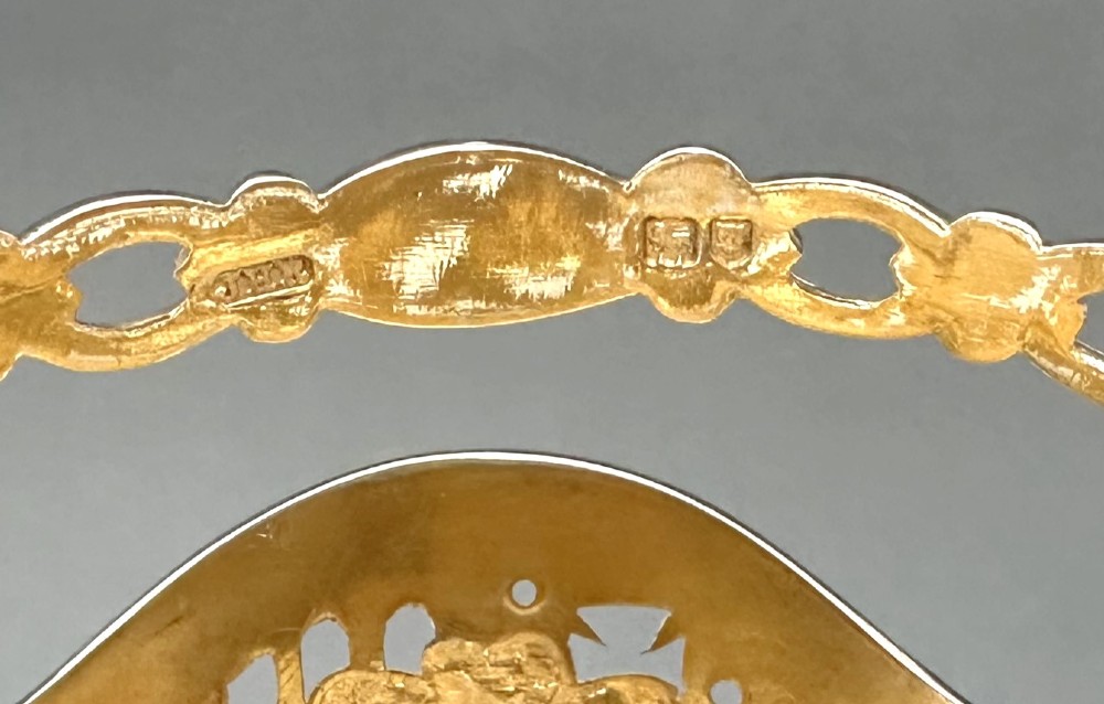 A pierced silver-gilt sugar basket featuring drape and bow motifs with an overhead swing handle, housing a scalloped ruby red cranberry glass liner. View X