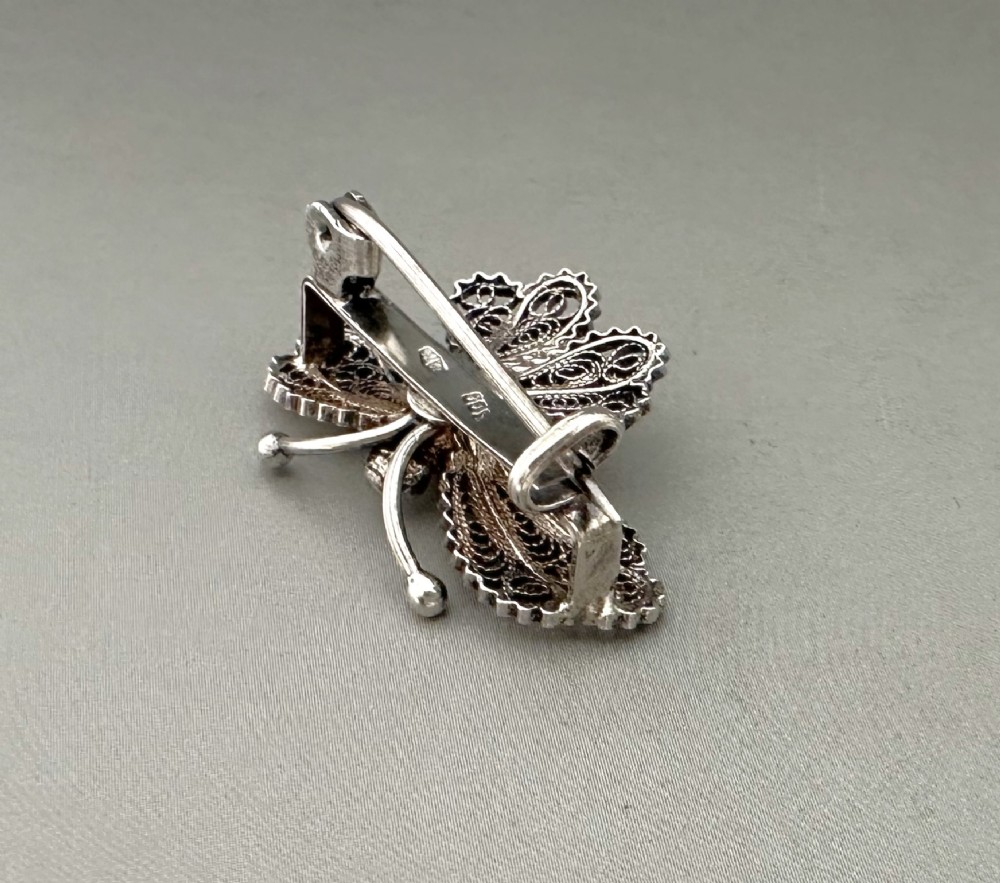 A sterling silver filigree brooch shaped like a butterfly with detailed openwork lace wings, textured body, and ball-tipped antennae. View III