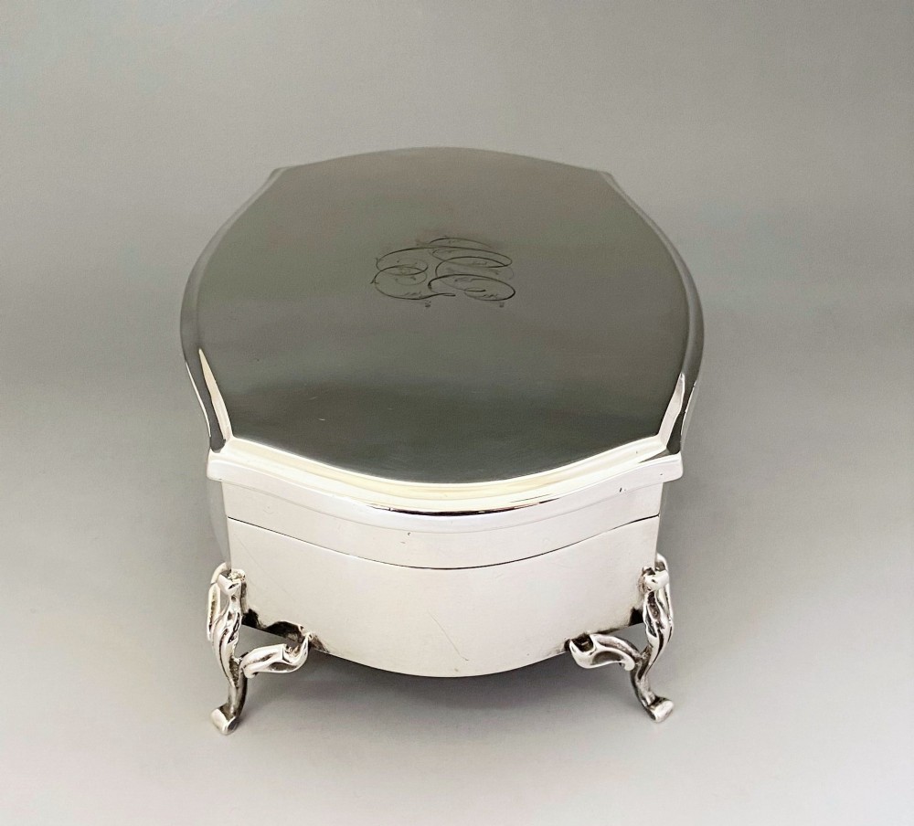 A silver jewellery trinket box with a hinged monogrammed lid supported on four decorative cabriole legs. View III