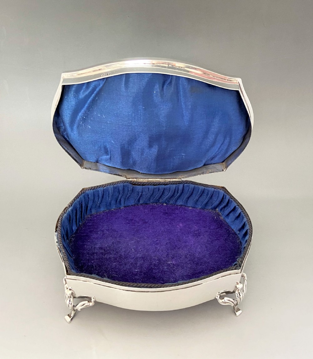 A silver jewellery trinket box with a hinged monogrammed lid supported on four decorative cabriole legs. View V