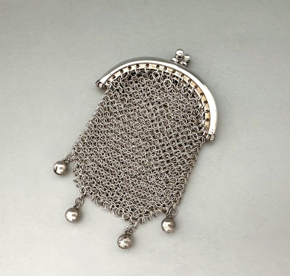 A petite French silver chainmail purse featuring a curved kiss-clasp frame and small silver spherical drops attached along the bottom seam.