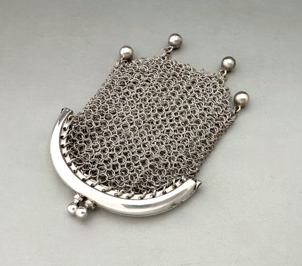 A petite French silver chainmail purse featuring a curved kiss-clasp frame and small silver spherical drops attached along the bottom seam. View III