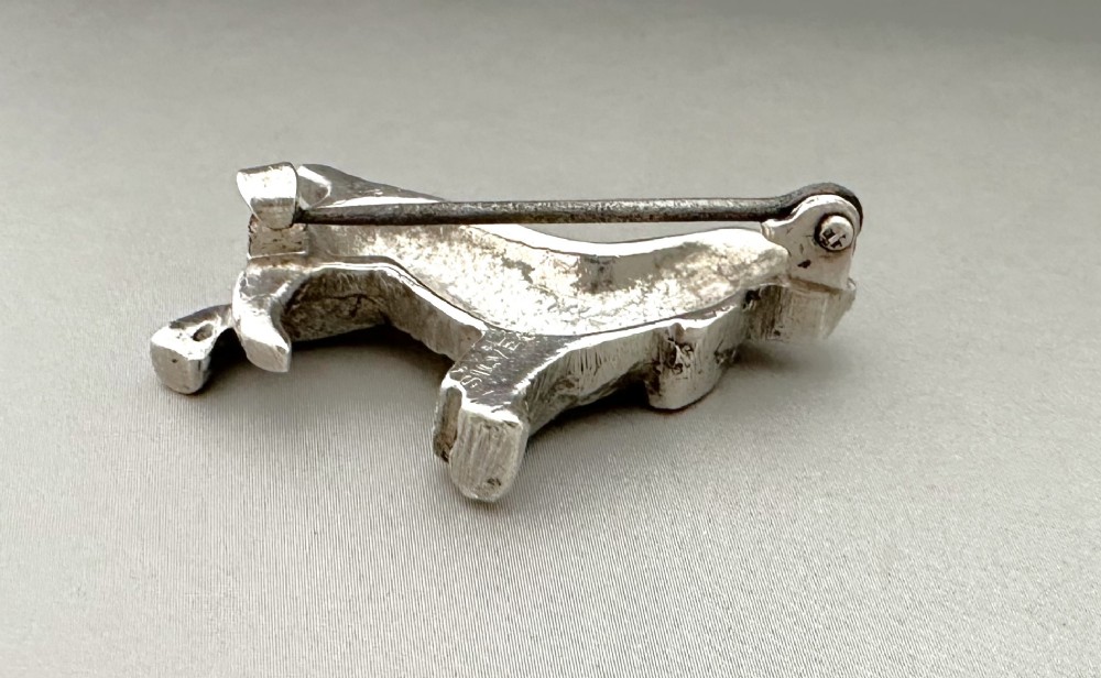 A cast silver brooch finely detailed in the shape of a standing spaniel dog with textured fur. View IV