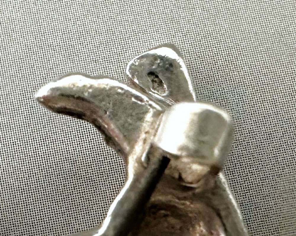 A cast silver brooch finely detailed in the shape of a standing spaniel dog with textured fur. View V