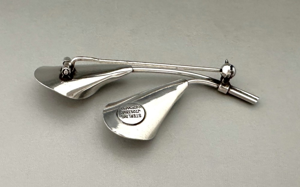 A sterling silver brooch depicting two stylized calla lily flowers with white engine-turned guilloche enamel petals. View II