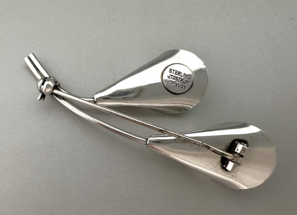 A sterling silver brooch depicting two stylized calla lily flowers with white engine-turned guilloche enamel petals. View III