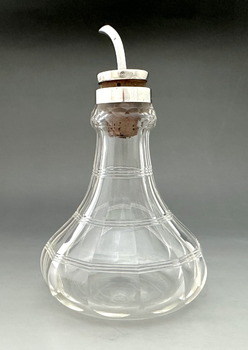 An Art Deco clear faceted glass bitters bottle featuring a hallmarked silver collar and curved pouring spout stopper. View III