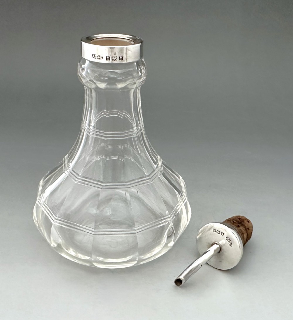 An Art Deco clear faceted glass bitters bottle featuring a hallmarked silver collar and curved pouring spout stopper. View IV