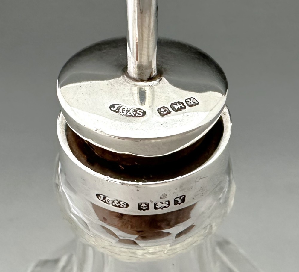 An Art Deco clear faceted glass bitters bottle featuring a hallmarked silver collar and curved pouring spout stopper. View VII