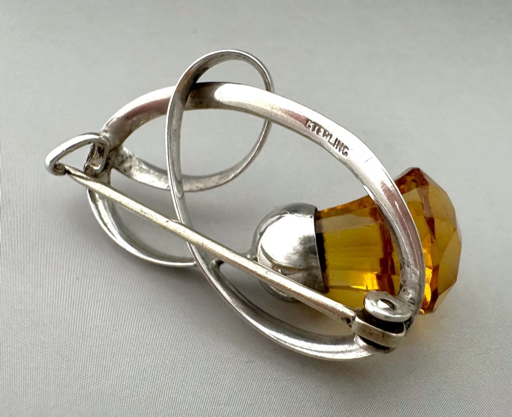 An Edwardian silver brooch designed in an openwork loop motif featuring a stylized Scottish thistle set with a faceted amber-coloured stone. View III