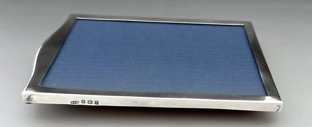 A rectangular sterling silver photo frame featuring a gently arched top edge, hallmark stamps along the side, and a dark blue insert. View VI