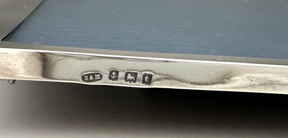 A rectangular sterling silver photo frame featuring a gently arched top edge, hallmark stamps along the side, and a dark blue insert. View VII