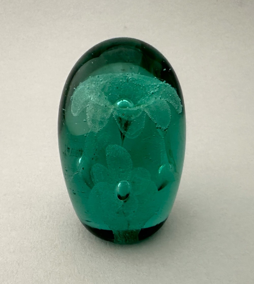 A heavy oval green glass paperweight displaying an internal controlled bubble floral motif. View III