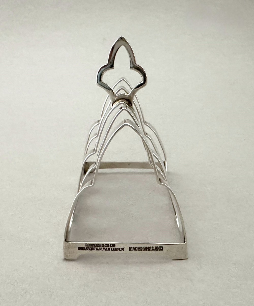 A hallmarked silver four-slice toast rack featuring shaped Gothic arch dividers and a central pierced top handle. View IV