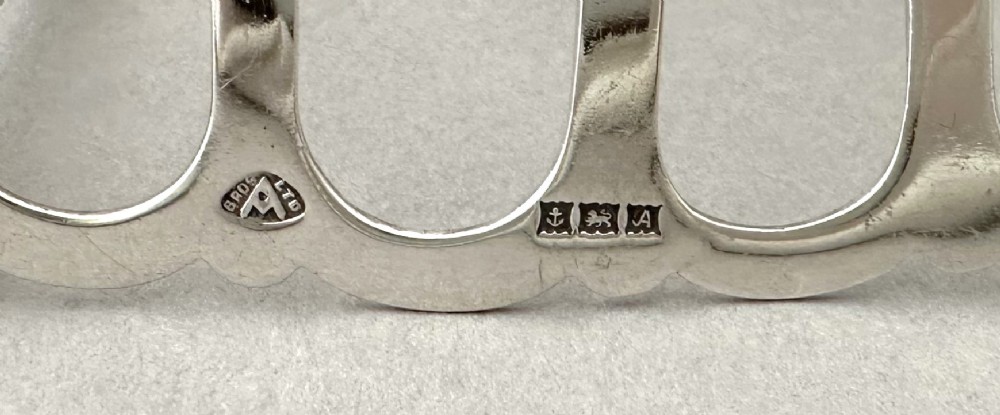 A hallmarked silver four-slice toast rack featuring shaped Gothic arch dividers and a central pierced top handle. View VII