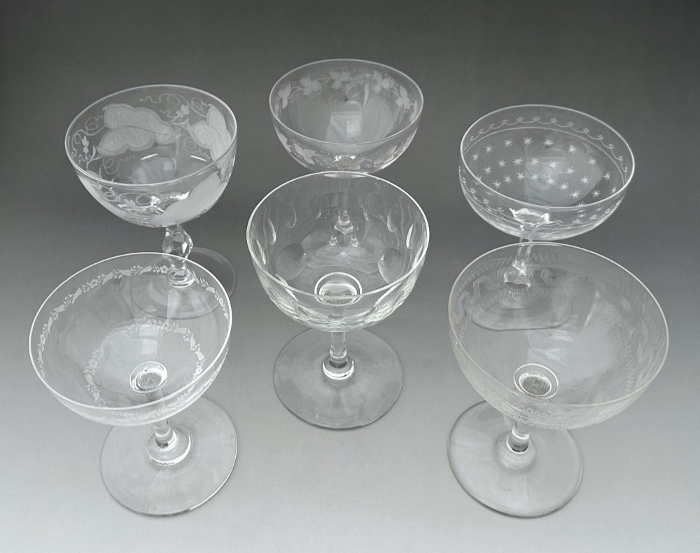 A harlequin set of six antique clear glass champagne coupes featuring various hand-etched geometric and floral patterns. View II