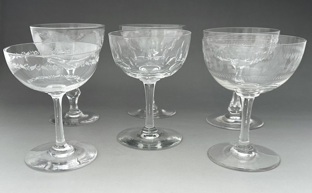 A harlequin set of six antique clear glass champagne coupes featuring various hand-etched geometric and floral patterns. View III