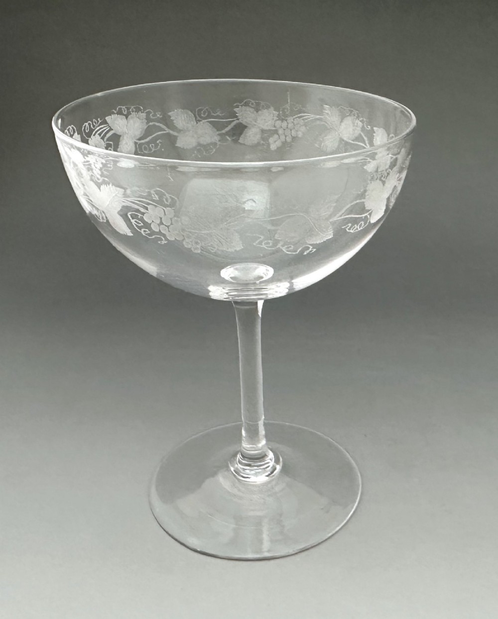 A harlequin set of six antique clear glass champagne coupes featuring various hand-etched geometric and floral patterns. View VIII