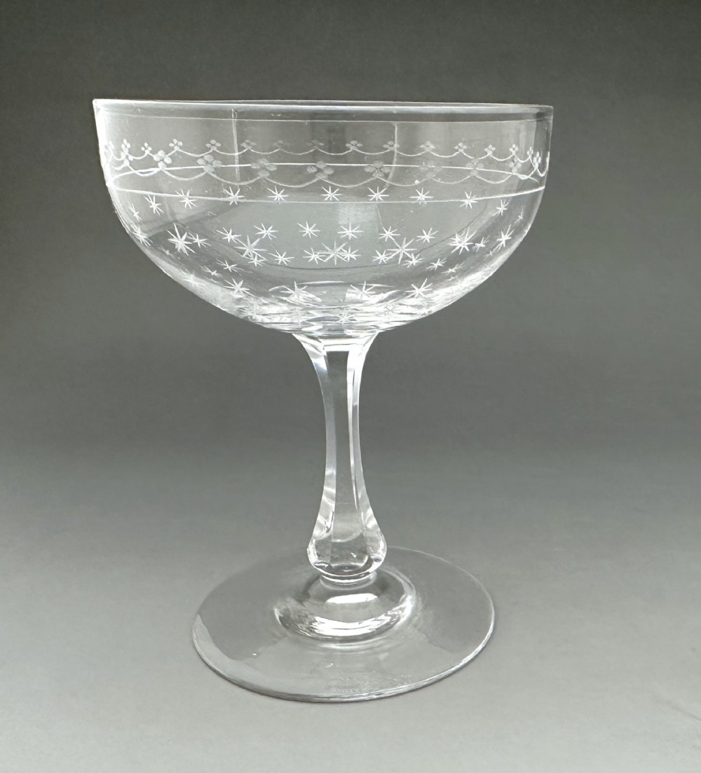 A harlequin set of six antique clear glass champagne coupes featuring various hand-etched geometric and floral patterns. View X