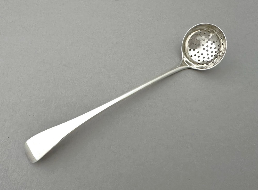 A Georgian sterling silver sifting ladle featuring a pierced round bowl and a smooth tapered handle. View III