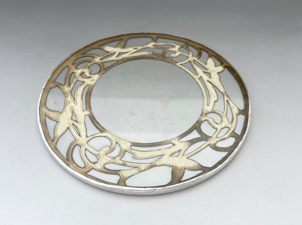 A circular clear glass teapot stand featuring a sterling silver rim with openwork Art Nouveau leaf motifs. View III