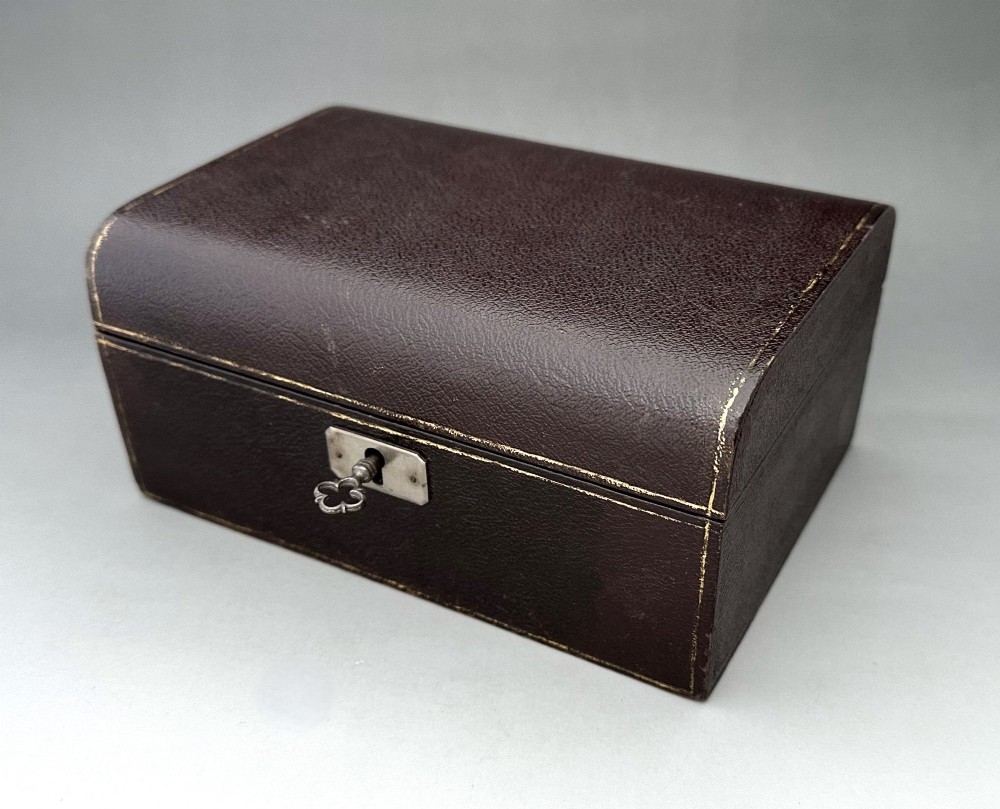 A dark brown leather Victorian jewellery box with a domed lid, subtle gilt edge tooling, and a metal keyhole escutcheon.