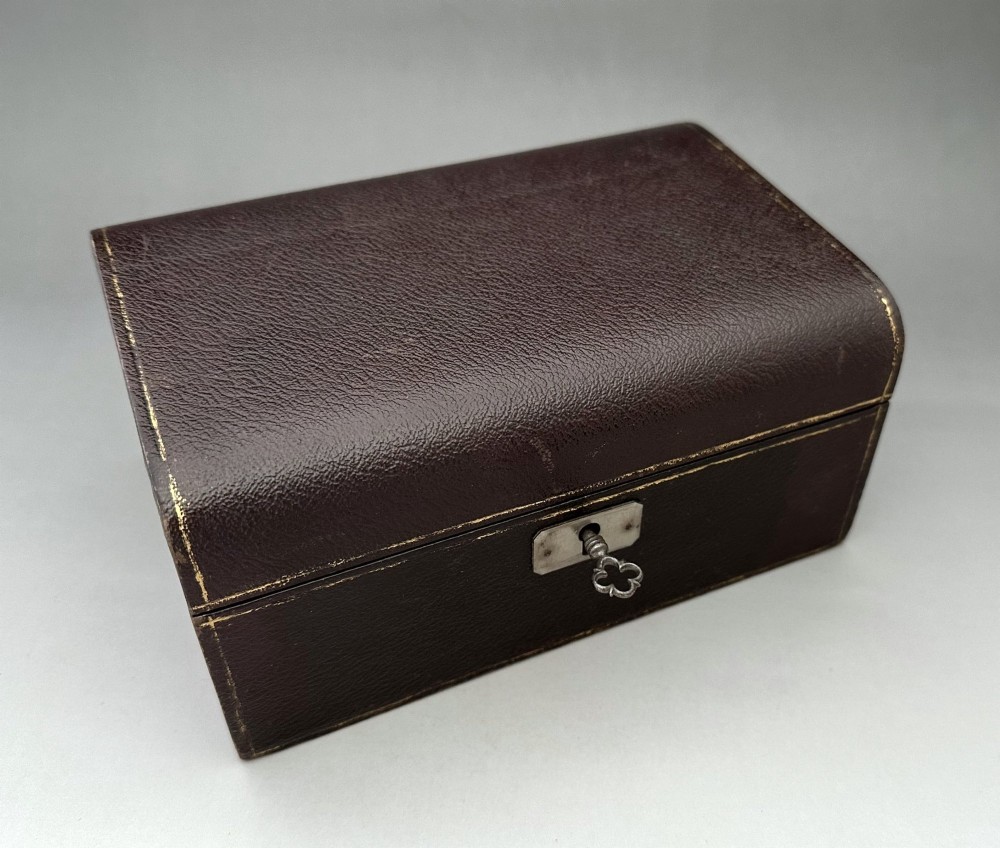 A dark brown leather Victorian jewellery box with a domed lid, subtle gilt edge tooling, and a metal keyhole escutcheon. View II