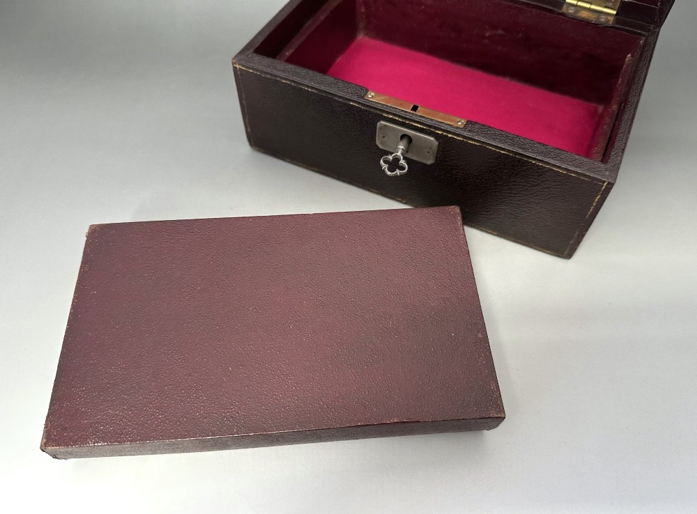 A dark brown leather Victorian jewellery box with a domed lid, subtle gilt edge tooling, and a metal keyhole escutcheon. View V