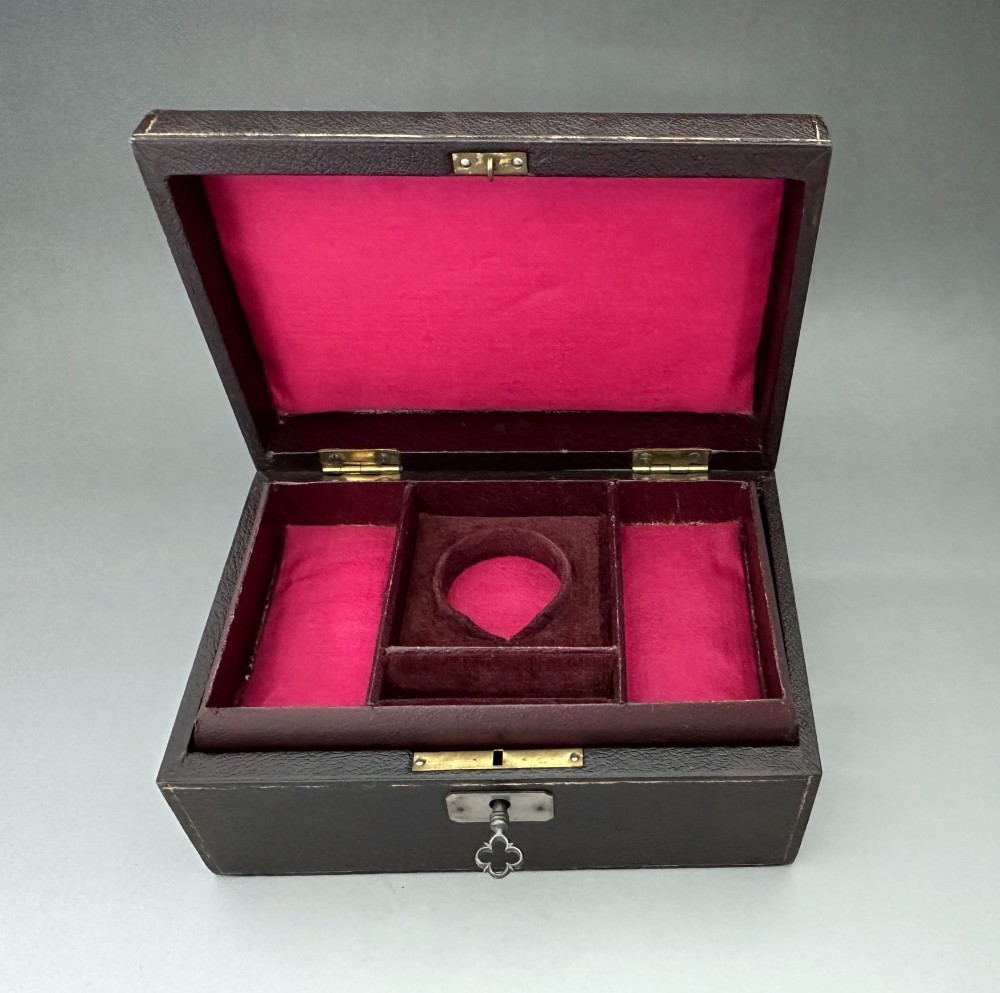A dark brown leather Victorian jewellery box with a domed lid, subtle gilt edge tooling, and a metal keyhole escutcheon. View VI