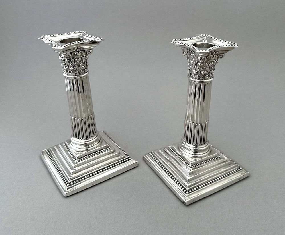 A pair of polished silver candlesticks crafted in the form of fluted Corinthian columns with acanthus capitals and stepped square bases. View III