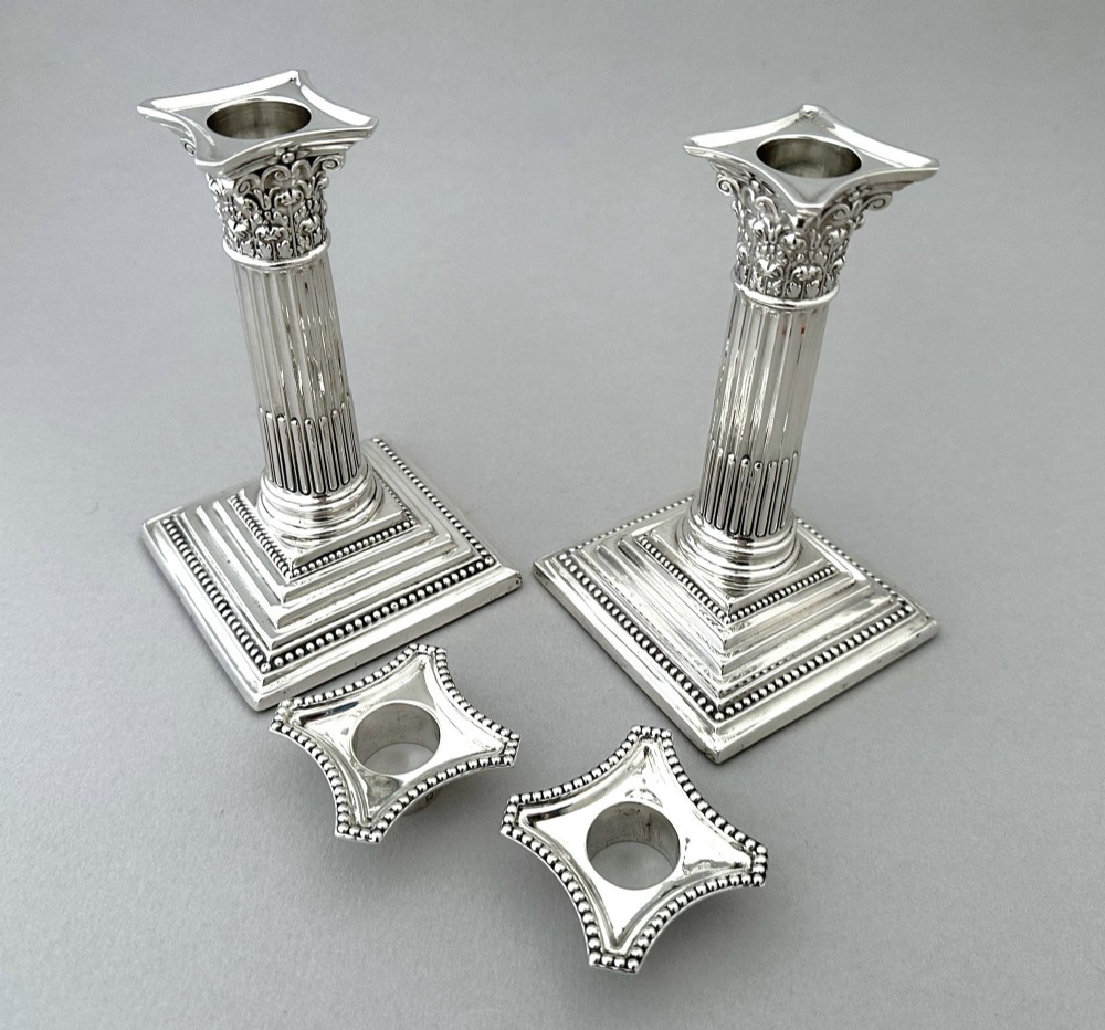 A pair of polished silver candlesticks crafted in the form of fluted Corinthian columns with acanthus capitals and stepped square bases. View IV