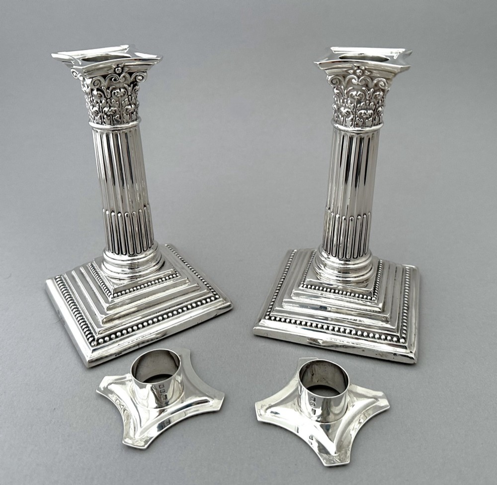 A pair of polished silver candlesticks crafted in the form of fluted Corinthian columns with acanthus capitals and stepped square bases. View VI