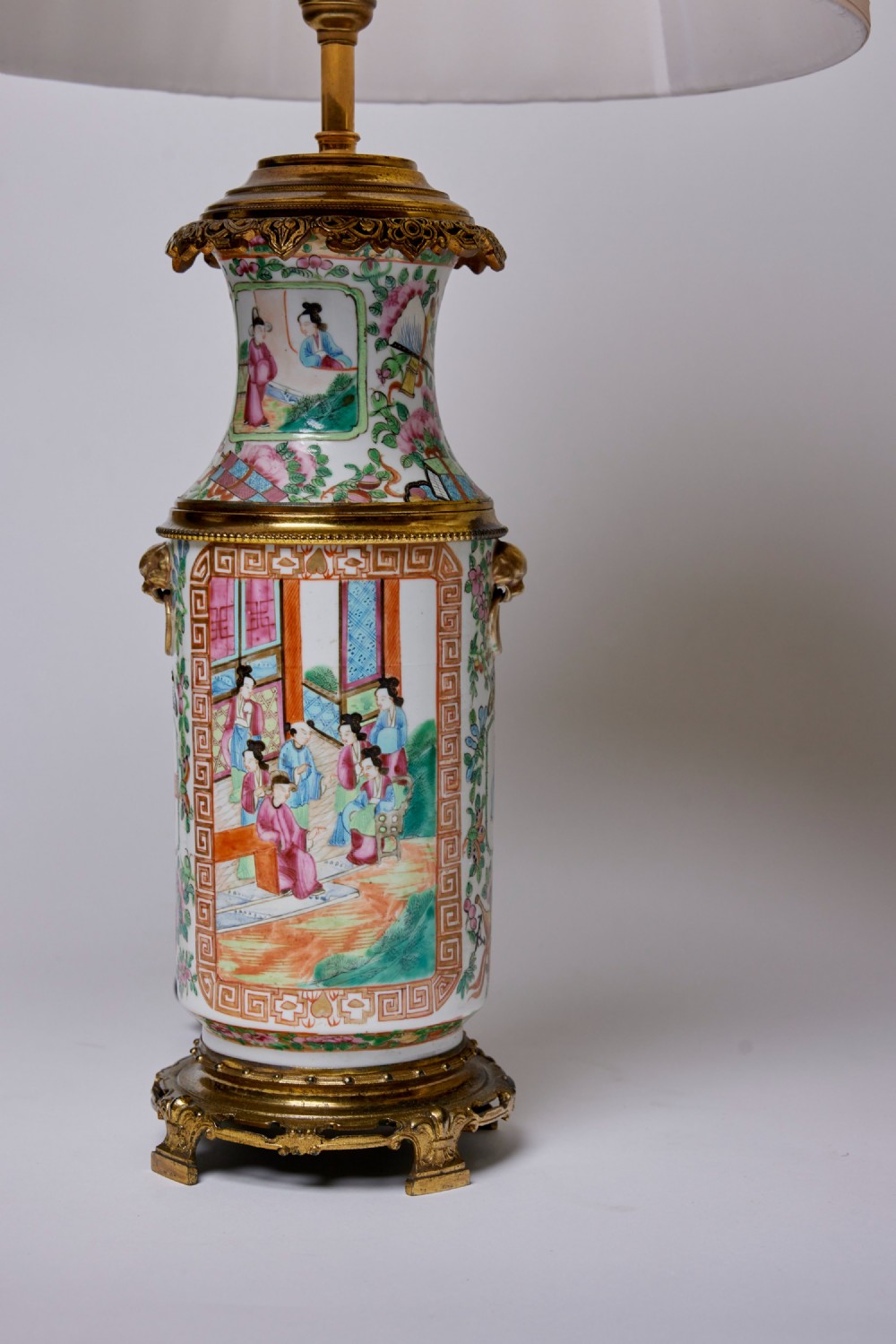 A pair of Chinese porcelain vase table lamps with hand-painted figures, gilt metal mounts, and cream pleated fabric shades. View II