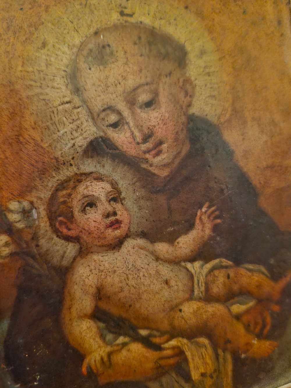 An antique Italian devotional icon depicting a saint holding the Christ Child set within a wide ebonised wooden frame with a gilded inner moulding. View III