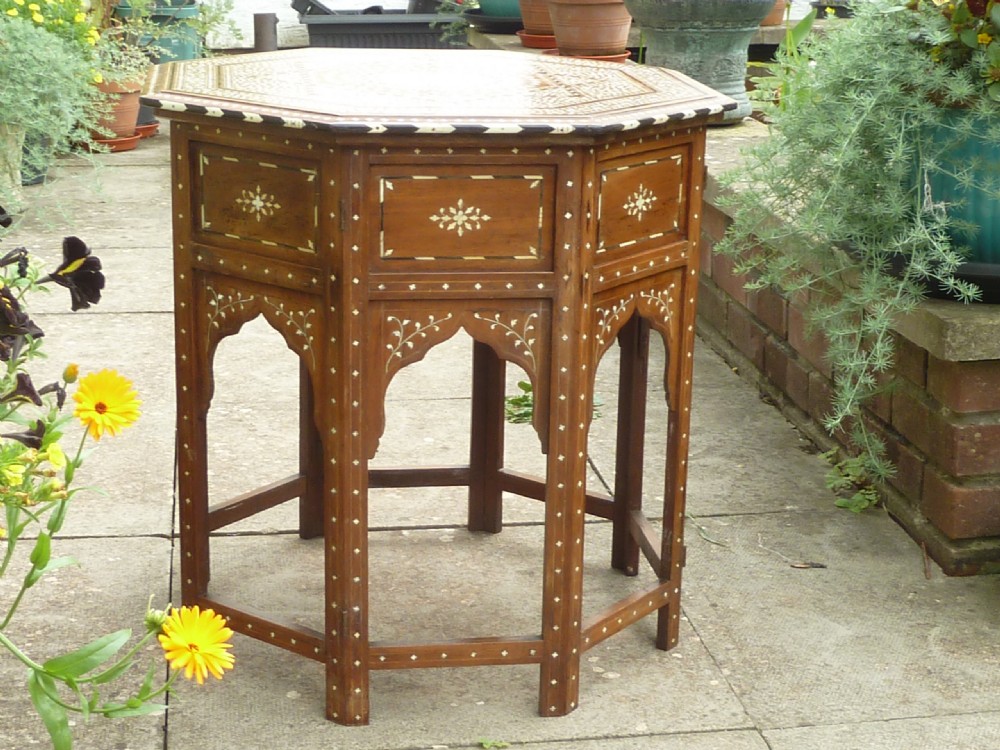 An Anglo-Indian octagonal wooden table featuring intricate bone inlay with geometric and floral motifs above Moorish arched lower aprons.
