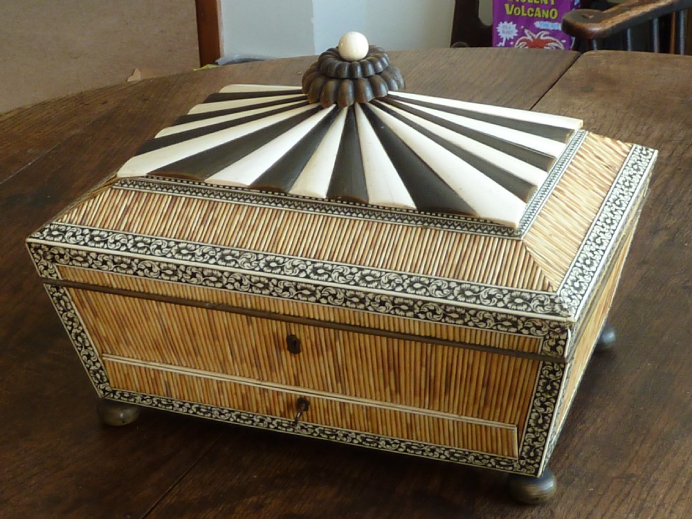 An Anglo-Indian sarcophagus-form workbox featuring porcupine quill panels, engraved bone borders, and a sunburst horn and bone lid finial.