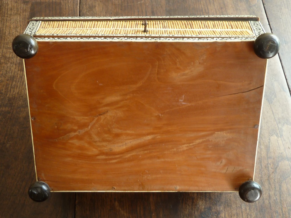 An Anglo-Indian sarcophagus-form workbox featuring porcupine quill panels, engraved bone borders, and a sunburst horn and bone lid finial. View X