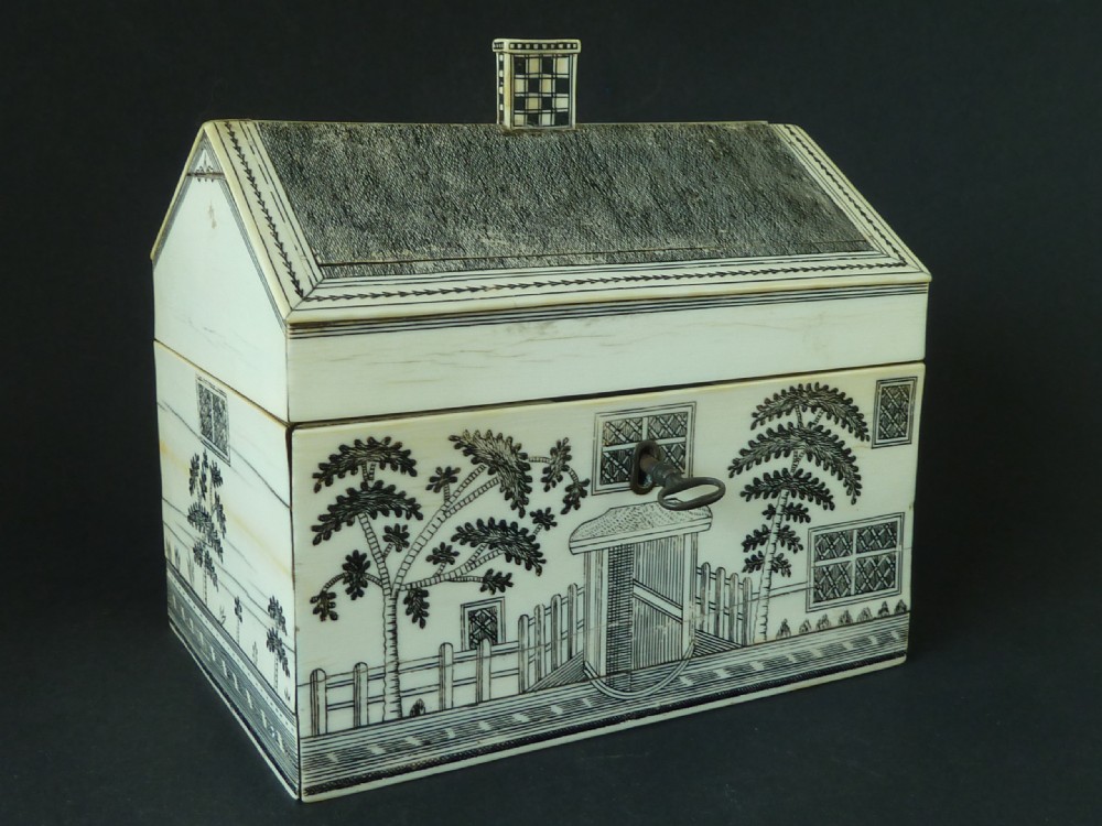 A house-shaped antique Anglo-Indian sewing box clad in ivory panels with black lac-engraved architectural details, trees, and a pitched roof.