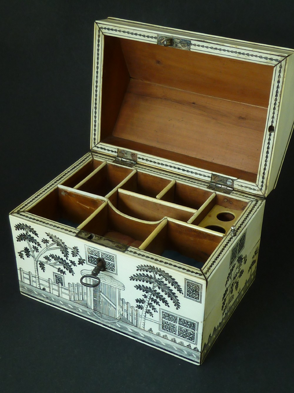 A house-shaped antique Anglo-Indian sewing box clad in ivory panels with black lac-engraved architectural details, trees, and a pitched roof. View VII