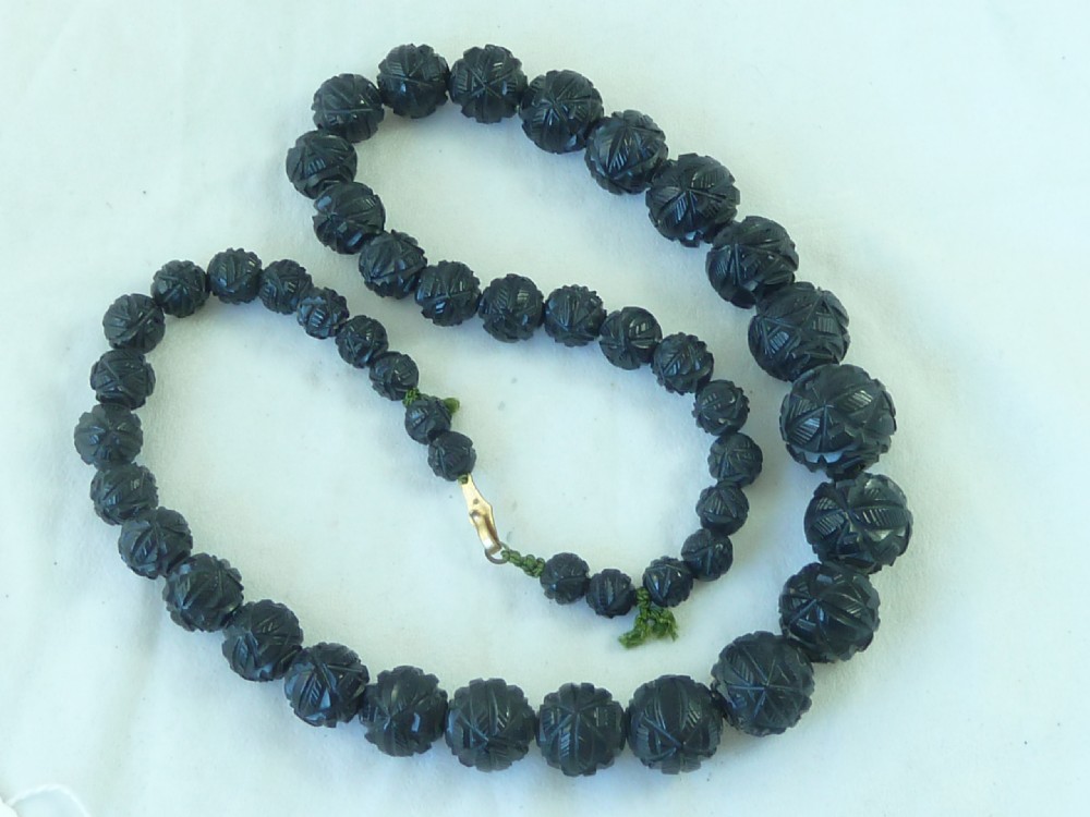 A strand of graduated Victorian Whitby jet beads with hand-carved geometric patterns.