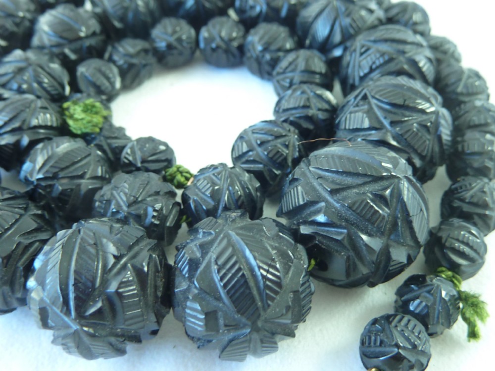 A strand of graduated Victorian Whitby jet beads with hand-carved geometric patterns. View V