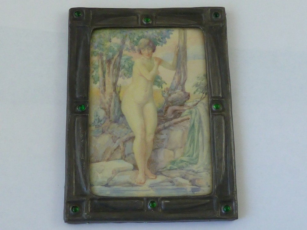 A rectangular Art Deco miniature painting of a nude female figure amongst trees, enclosed in a dark metal frame inset with green glass cabochons. View II