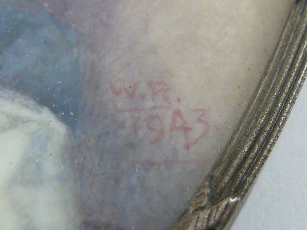 An oval hand-painted portrait miniature depicting a seated female nude resting on white drapery set in a thin metal frame. View IV