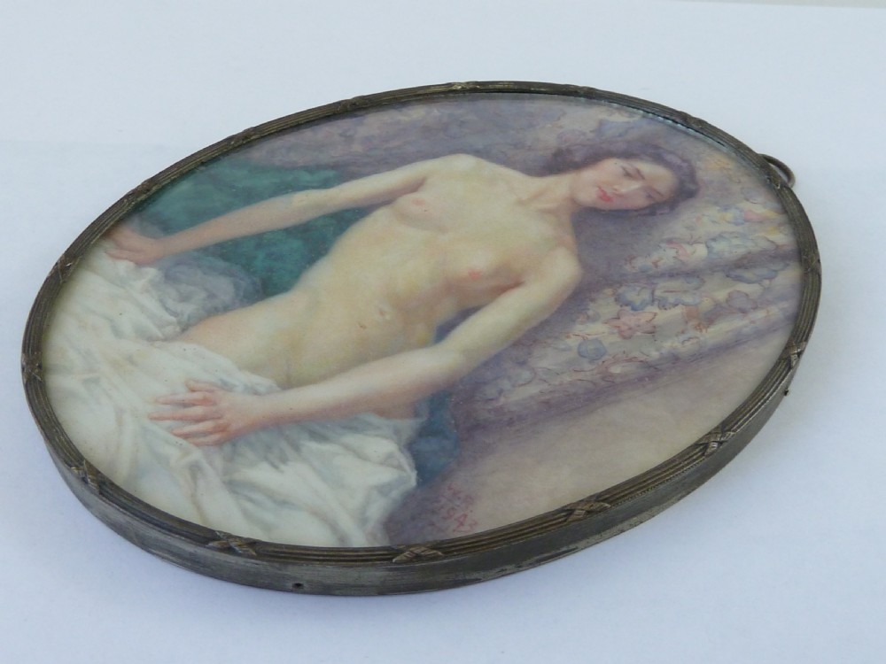 An oval hand-painted portrait miniature depicting a seated female nude resting on white drapery set in a thin metal frame. View VI