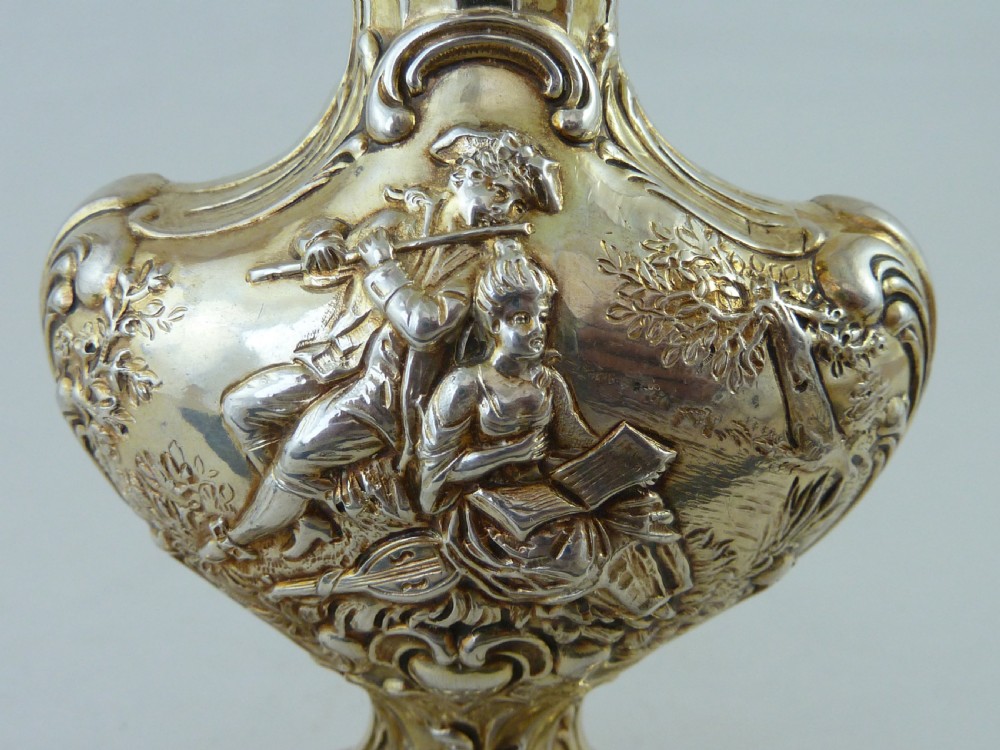 A Hanau silver gilt sugar caster featuring elaborate Rococo relief scenes of figures in a landscape and a pierced finial lid. View IX
