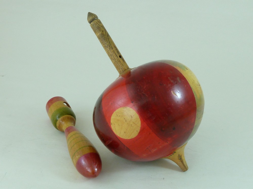 A turned wooden humming spinning top featuring polychrome painted bands in red, green, and yellow with an attached turned wooden handle. View V