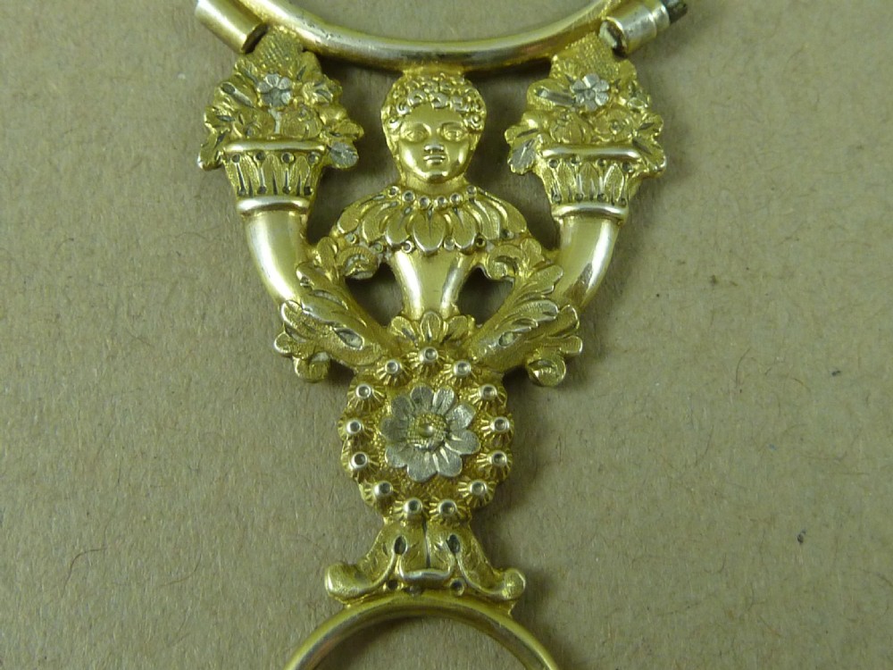 A French silver-gilt figural quizzing glass featuring an ornate central figure handle and a circular lens frame. View IV
