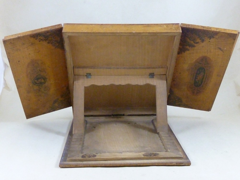 A Victorian Mauchline ware folding wooden reading stand in pale wood featuring black transfer prints of classical figures across three panels. View VI