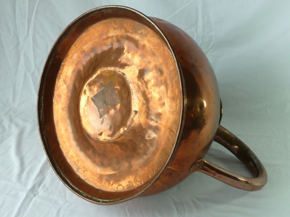 A large Victorian copper four-gallon measure featuring a bulbous lower body, flared conical spout, and a thick curved metal handle. View VII